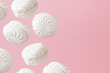 White zephyr marshmallows on light pastel pink background banner with an empty space