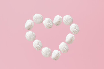 Heart shaped figure of white zephyr on a pink pastel background