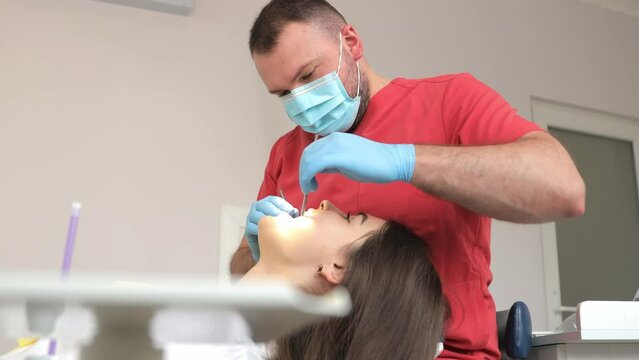 Male dentist examining teeth of female patient.