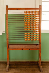 An abacus standing in the classroom near green wall.