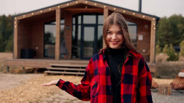 Close-up portrait of a beautiful girl looking straight into the camera and smiling against the background of wooden house in forest