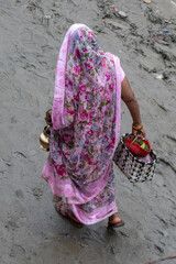 Woman walking along the banks of the Ganges River at a Ghat in Varanasi in India.