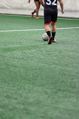 Player preparing to hit the ball on mini soccer match in sports hall.