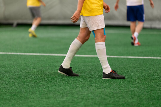 Futsal five-a-side players on artificial grass field indoor.