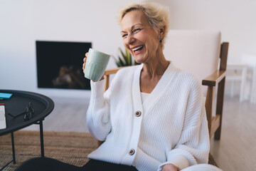 Laughing woman in cardigan with cup of drink