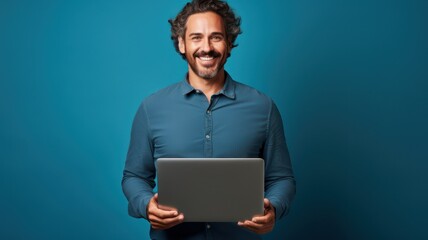 Happy 40 year old man in a blue shirt, smiling, standing on a blue background holding a laptop created with Generative AI - Powered by Adobe