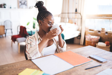 Black woman drinking coffee from mug at home