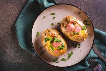 Close up of baked whole potatoes with egg, sausages and herbs on a plate top view