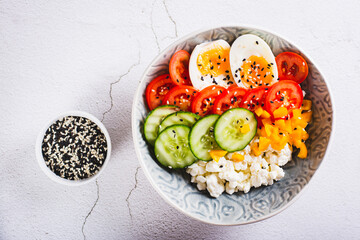 Close up of cottage cheese bowl with tomatoes, cucumber, pepper and egg on the table top view