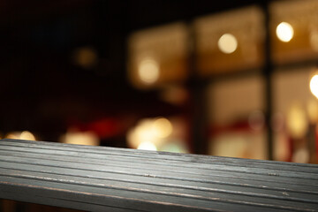 Wooden table top on blurred cafe showcase with light bulb. Background for product display montage...