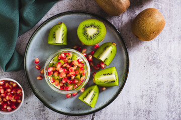Fresh Greek yogurt with kiwi pieces and pomegranate seeds in a glass on the table top view