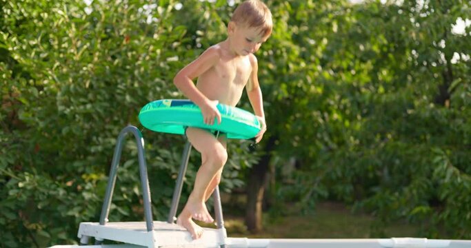 Joyful boy jumping into the pool in the backyard enjoying his summer vacation