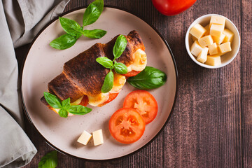 Croissant caprese sandwich baked with tomatoes and cheese on a plate top view