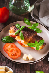 Baked caprese croissant with tomatoes, cheese and basil on a plate vertical view