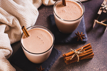 Homemade boozy holiday eggnog with cinnamon in glasses on the table