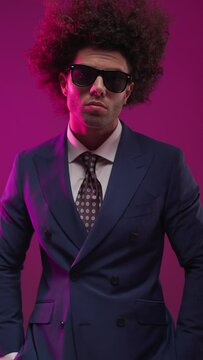 vertical video of confident high class businessman holding hands in pockets and looking forward and down when camera is closing up 