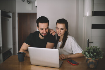 Positive young couple browsing laptop at home