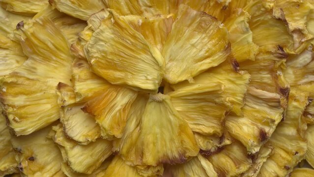 Dried pineapple pieces. Food background texture. Table spin.