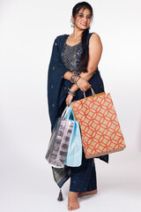 Portrait of young Indian woman or girl in a traditional dress carrying shopping bags during festival isolated over white background