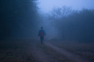Girl walking through a path with blue soft mist