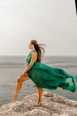 Woman sea green dress. Side view a happy woman with long hair in a long mint dress posing on a beach with calm sea bokeh lights on sunny day. Girl on the nature on blue sky background.