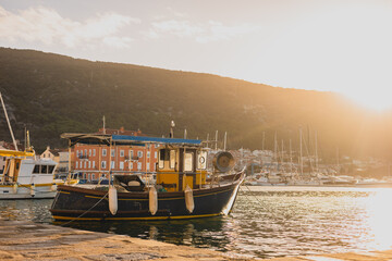 Fishing boat moored in early morning hours in the port of Cres. Lovely ol fishing boat on calm seas at a port. Sun slowly rising up behind a hill.