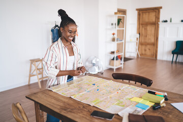 African American woman checking map over wooden table at home