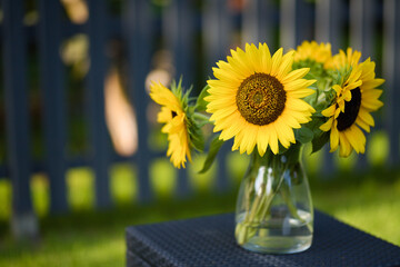 A glass vase of large sunflowers in an idyllic setting