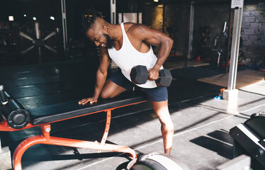 Fototapeta na wymiar Black man doing exercise with dumbbell in gym
