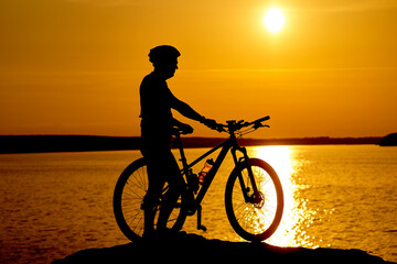 Fototapeta premium A Serene Beachscape With a Man and His Bicycle. A man standing next to a bike on top of a beach