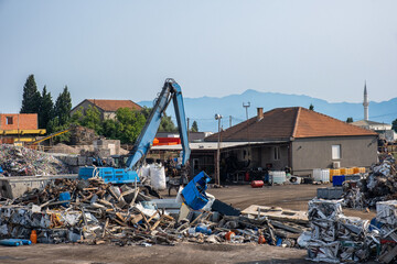 Grab crane works in waste recycling and sorting center. Scrap metal recycling center for sorting...