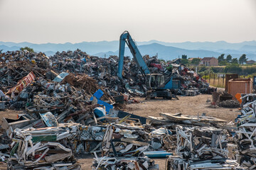 Clow crane picking up scrap metal at recycling center for metal, aluminum, brass, copper, stainless steel in junk yard. Recycling industry. Environment and zero waste concept - obrazy, fototapety, plakaty