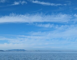  distant view of San Francisco across the bay, framed by a clear blue sky and scattered clouds