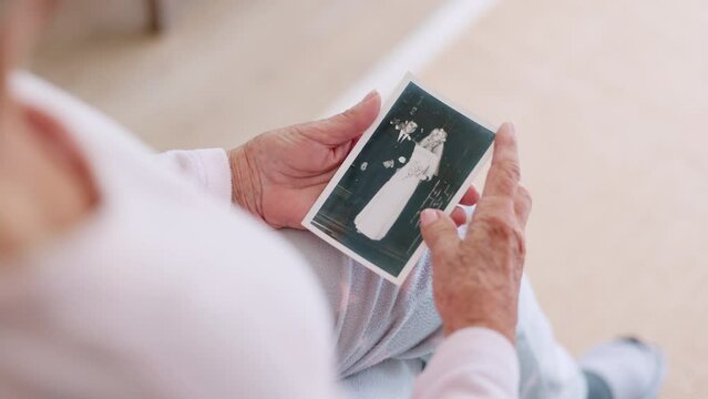 Senior, person and hold of photograph for memory in home of wedding, retro or vintage. Closeup, elderly woman and hand with picture of husband for love, caring or bond in marriage with retirement