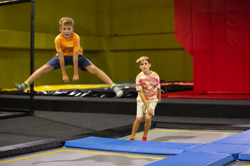 Expressive cheerful tween boy enjoying jumping on trampoline on indoor inflatable playground..