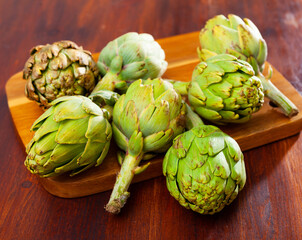 Obraz premium Fresh young buds of artichokes on wooden background. Natural vegetarian food concept..