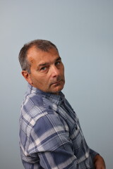 Portrait of mature male wearing plaid shirt turning his face towards camera
