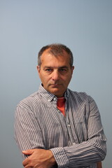 Portrait of middle aged male with crossed arms on flat gray background