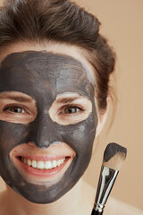 happy modern 40 years old woman with brush and facial mask