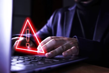 Hands of a businessman using the computer on fraudulent pages. Caution symbol of danger of hackers...