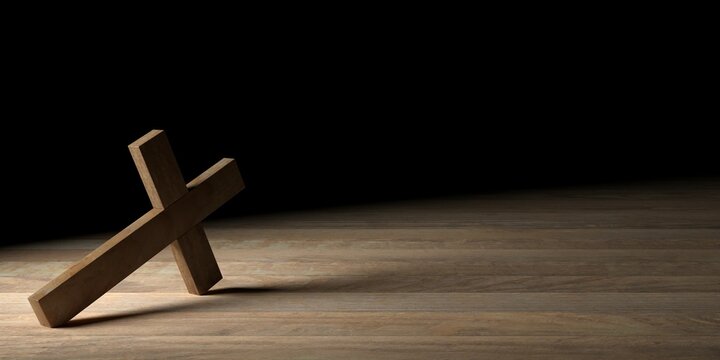 Wooden Jesus Christ christian crucifix or cross leaning on wood table with spotlight on black background with copy space, god, resurrection or christianity concept