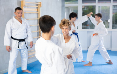 Fototapeta premium Diligent preteen karate students practicing fighting techniques during workout session