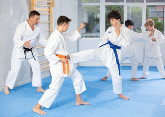 Fototapeta na wymiar Willing junior attendee of karate classes fighting with his opponent in sports hall