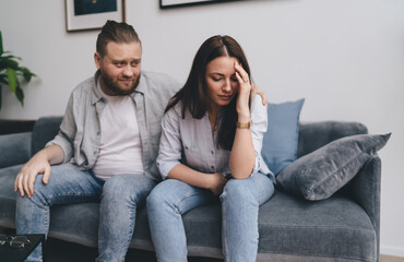 Stressed out couple sitting on sofa at home