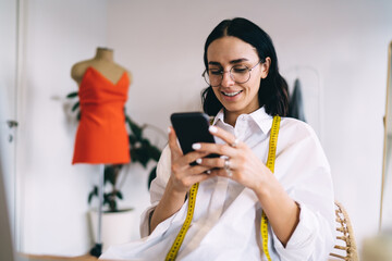 Cheerful woman using smartphone in atelier
