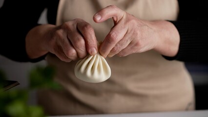 Delicious homemade food, Georgian cuisine. Khinkali production. Khinkali in the hands of the cook. The hands of the cook mold khinkali and put them on the table.
