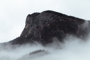 Fog over a snowy mountain of the Chartreuse mountain range in the French Alps during winter.