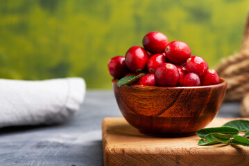 Fresh cranberries in a wooden bowl with spoon on dark wooden table. View from above.Space for text.