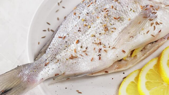Dorado fish with spices cooking on plate. Top view
