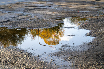 After the storm, fall leaves and streetlight reflecting in a large puddle in a broken up parking lot
